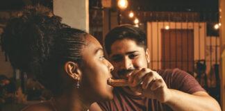 A man feeding a woman some churros